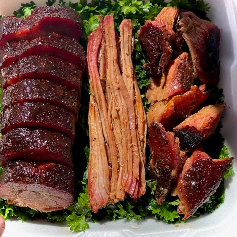 Competition brisket trio — sliced brisket, pulled brisket, and burnt ends on a bed of parsley